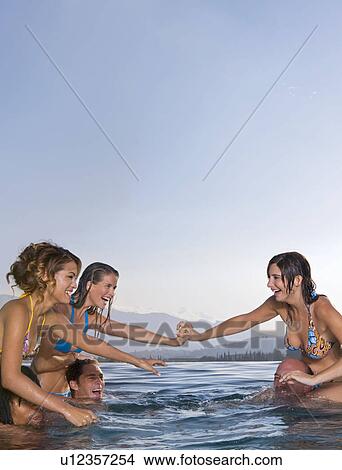 Picture - Young men and women playing in a pool. Fotosearch