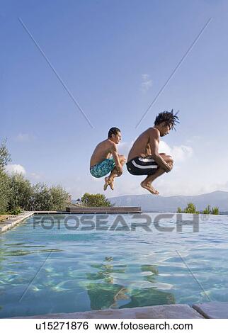 Young men jumping into a pool View Large Photo Image Stock Photograph - Young men jumping into a pool. Fotosearch