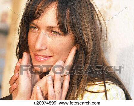 Stock Photo - Woman touching man's hands on face, smiling. Fotosearch