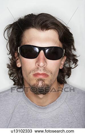 Stock Image - Young male with long hair wearing sunglasses. Fotosearch