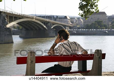 Businessman sitting alone on Bench by river. View Large Photo Image Stock Image - Businessman sitting alone on Bench by river.. Fotosearch