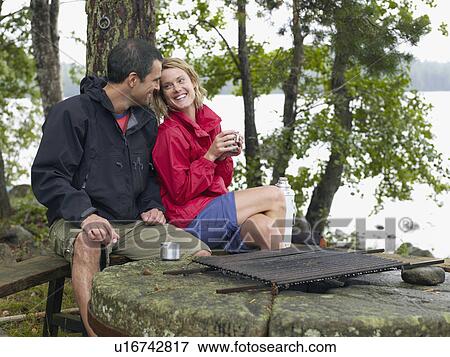 Couple sitting in a park by a fire pit smiling. View Large Photo Image Stock Photo - Couple sitting in a park by a fire pit smiling.. Fotosearch