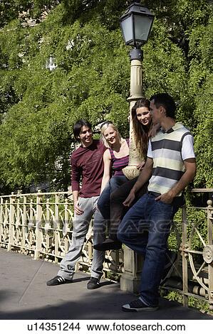 Four friends leaning on bridge rail smiling. View Large Photo Image Picture - Four friends leaning on bridge rail smiling.. Fotosearch