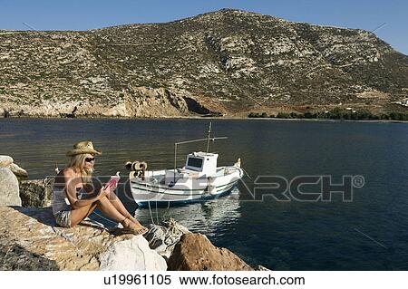 Woman reading a book on large rocks by a boat. View Large Photo Image Stock Photography - Woman reading a book on large rocks by a boat.. Fotosearch