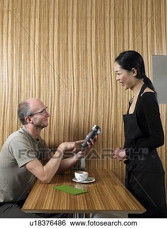 Mature man using credit card reader to pay waitress View Large Photo Image Stock Photograph - Mature man using credit card reader to pay waitress. Fotosearch