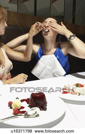 Two women in a restaurant feeding each other View Large Photo Image Stock Photo - Two women in a restaurant feeding each other. Fotosearch