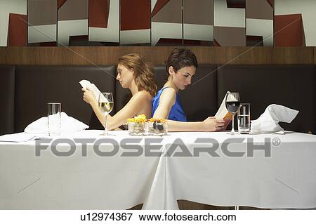 Two women in a restaurant reading View Large Photo Image Stock Photo - Two women in a restaurant reading. Fotosearch