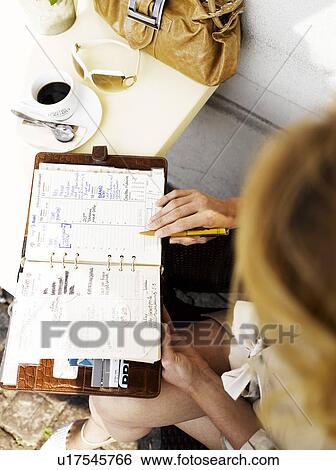Woman at an outdoor restaurant with her day planner View Large Photo Image Stock Photograph - Woman at an outdoor restaurant with her day planner. Fotosearch