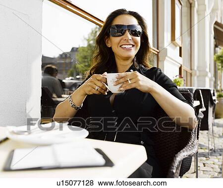 Woman drinking coffee at an outdoor restaurant View Large Photo Image Stock Photo - Woman drinking coffee at an outdoor restaurant. Fotosearch