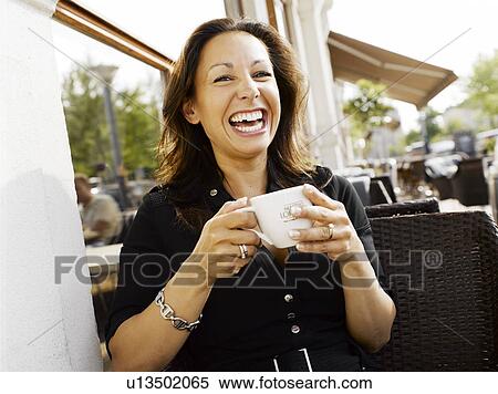 Stock Photography - Woman drinking coffee at an outdoor restaurant. Fotosearch