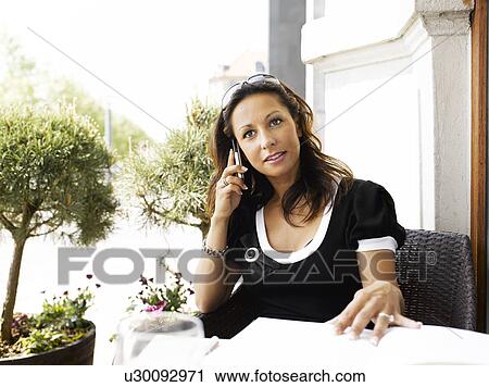 Woman on her cell phone at an outdoor restaurant View Large Photo Image Stock Image - Woman on her cell phone at an outdoor restaurant. Fotosearch