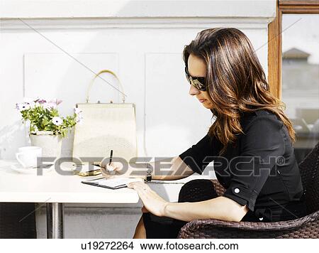 Woman taking notes at an outdoor restaurant View Large Photo Image Picture - Woman taking notes at an outdoor restaurant. Fotosearch