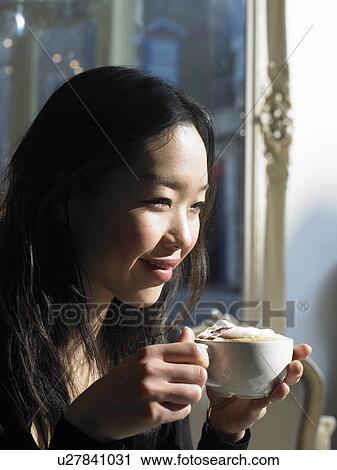 Young woman holding cappuccino, smiling, close-up View Large Photo Image Stock Image - Young woman holding cappuccino, smiling, close-up. Fotosearch