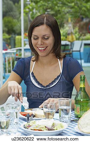 Young woman on table in Greek tavern in front of plates slicing her food happy. View Large Photo Image Stock Image - Young woman on table in Greek tavern in front of plates slicing her food happy.. Fotosearch