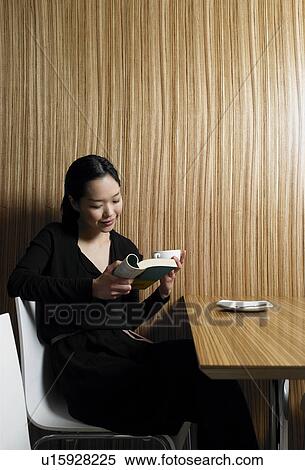 Young woman reading book in wood paneled café View Large Photo Image Stock Photography - Young woman reading book in wood paneled café. Fotosearch