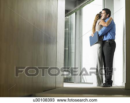 Stock Image - A woman hugging a man in a hallway. Fotosearch