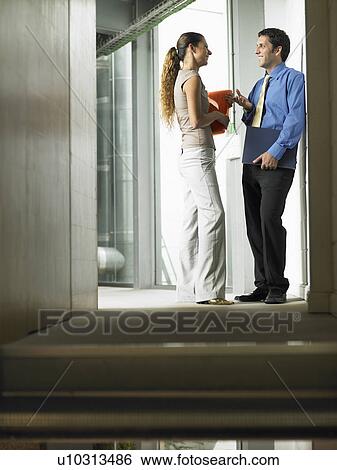 A woman talking to a man in a hallway View Large Photo Image Stock Photograph - A woman talking to a man in a hallway. Fotosearch