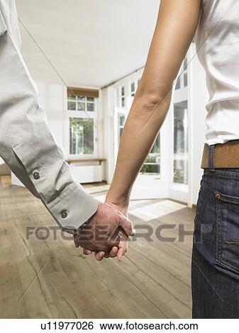 Close up on hands holding together of a couple in an empty house. View Large Photo Image Stock Photograph - Close up on hands holding together of a couple in an empty house.. Fotosearch