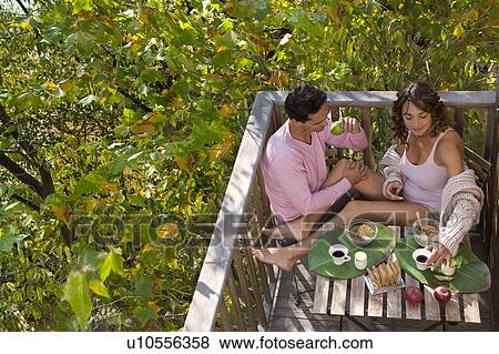Stock Photo - Couple eating breakfast outdoors smiling.. Fotosearch