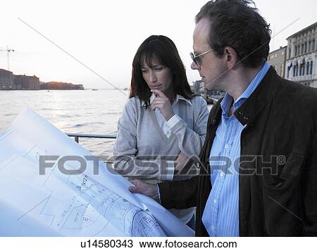 Stock Image - Couple looking at architect's blueprint. Venice, Italy.. Fotosearch