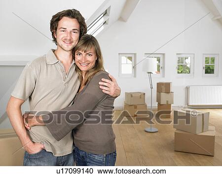 Stock Image - Couple moving into new home smiling.. Fotosearch