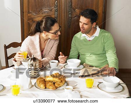 Couple sitting at breakfast table, talking View Large Photo Image Stock Photo - Couple sitting at breakfast table, talking. Fotosearch