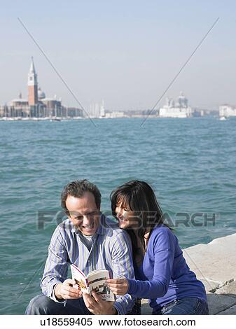 Couple sitting looking at guide book. Venice, Italy. View Large Photo Image Stock Photography - Couple sitting looking at guide book. Venice, Italy.. Fotosearch