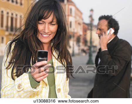 Man and woman using mobile phones. Venice, Italy. View Large Photo Image Stock Photograph - Man and woman using mobile phones. Venice, Italy.. Fotosearch