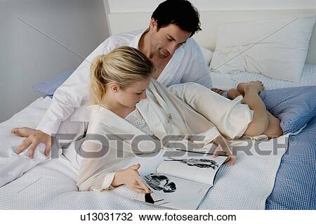 Stock Image - Portrait of a couple laying on a bed.. Fotosearch