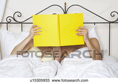 young couple in bed holding yellow book up together View Large Photo Image Stock Image - young couple in bed holding yellow book up together. Fotosearch