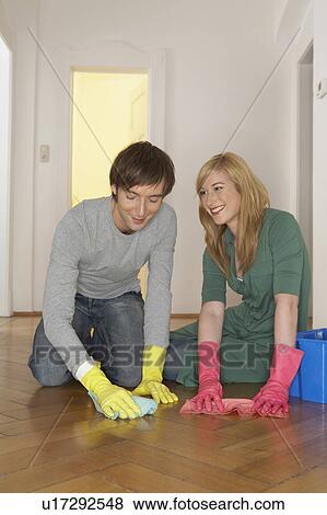 Stock Photo - Young couple polishing wooden floor, smiling. Fotosearch