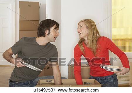 Young couple unpacking cardboard box, smiling View Large Photo Image Stock Photo - Young couple unpacking cardboard box, smiling. Fotosearch