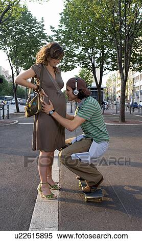 Young man crouching at pregnant young woman's stomach, smiling View Large Photo Image Stock Photography - Young man crouching at pregnant young woman's stomach, smiling. Fotosearch
