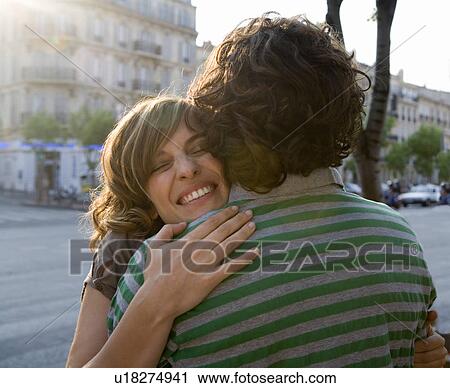 Young woman embracing young man in street, smiling, close-up View Large Photo Image Stock Image - Young woman embracing young man in street, smiling, close-up. Fotosearch