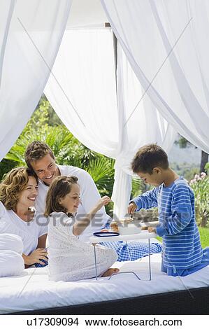 Family having breakfast on bed in garden View Large Photo Image Picture - Family having breakfast on bed in garden. Fotosearch