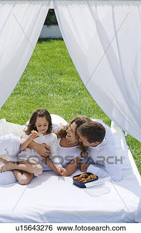 Family having breakfast on bed in garden View Large Photo Image Stock Photograph - Family having breakfast on bed in garden. Fotosearch
