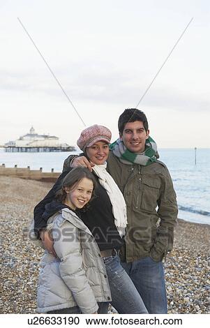 Stock Image - Happy couple and girl on beach. Fotosearch