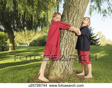 Young boy and girl hugging tree View Large Photo Image Picture - Young boy and girl hugging tree. Fotosearch