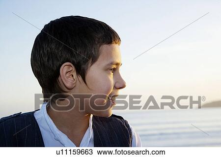 Stock Image - Young boy looking out to sea. Fotosearch