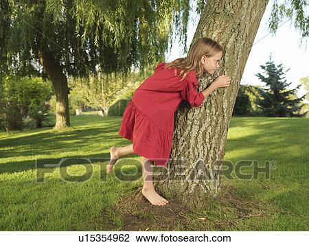 Young girl hiding behind tree View Large Photo Image Stock Image - Young girl hiding behind tree. Fotosearch