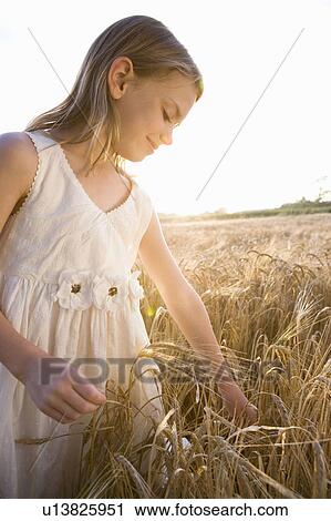Stock Image - Young girl standing in corn field. Fotosearch