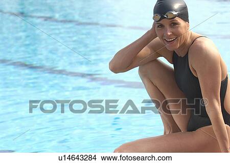 Picture - Female swimmer sitting by pool, smiling, portrait. Fotosearch