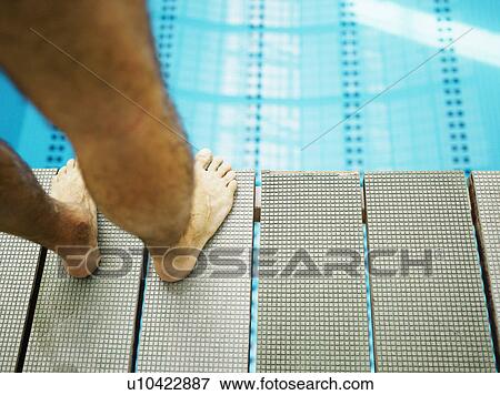 Stock Photo - Man standing on diving board, close-up, low section. Fotosearch