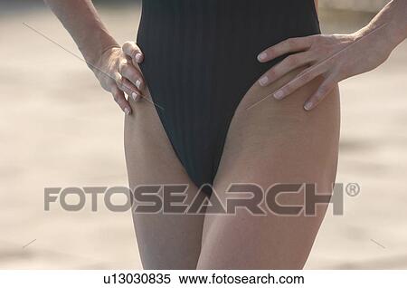 Woman wearing swimming costume standing with hands on hips, mid section View Large Photo Image Stock Photography - Woman wearing swimming costume standing with hands on hips, mid section. Fotosearch