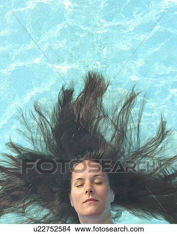 Woman with long hair floating in swimming pool, eyes closed View Large Photo Image Picture - Woman with long hair floating in swimming pool, eyes closed. Fotosearch