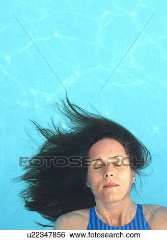 Woman with long hair floating in swimming pool, eyes closed View Large Photo Image Stock Photograph - Woman with long hair floating in swimming pool, eyes closed. Fotosearch
