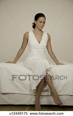 Stock Photography - Portrait of a woman sitting on a bed. Fotosearch