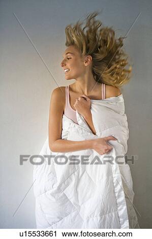 Stock Image - Young woman wrapped in a duvet. Fotosearch