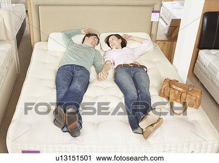 Couple lying on bed in furniture store. View Large Photo Image Stock Image - Couple lying on bed in furniture store.. Fotosearch