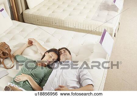 Couple lying on bed in furniture store. View Large Photo Image Stock Photograph - Couple lying on bed in furniture store.. Fotosearch